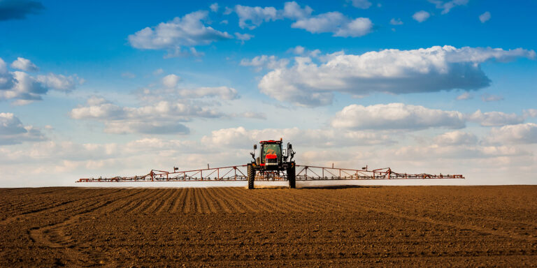 Tractor applying herbicide to open field