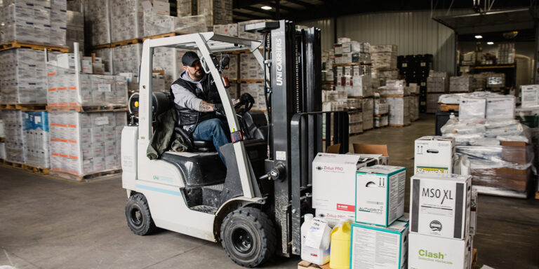 Man driving forklift carrying agriculture input supplies